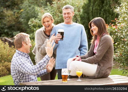 Group Of Friends Outdoors Enjoying Drink In Pub Garden