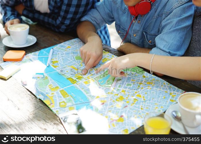 Group of friends planing a trip and looking at a map at a coffee. Travel concept.