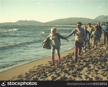 Group of friends running on beach during autumn day. group of young friends spending day together running on the beach during autumn day colored filter