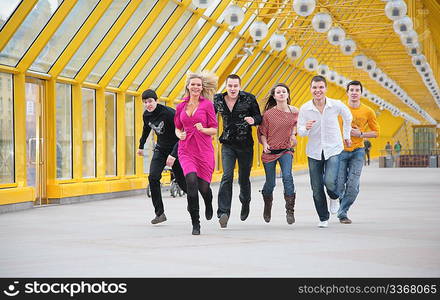 group of friends runs on yellow footbridge