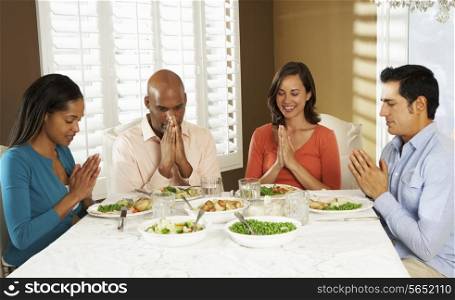 Group Of Friends Saying Grace Before Meal At Home