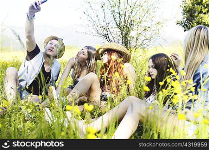 Group of friends sitting in grass photographing themselves