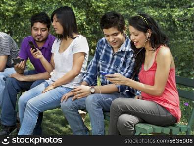 Group of friends sitting on a bench using mobile phone