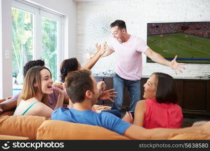 Group Of Friends Sitting On Sofa Watching Soccer Together