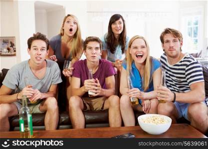 Group Of Friends Sitting On Sofa Watching Sport Together