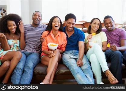 Group Of Friends Sitting On Sofa Watching TV Together