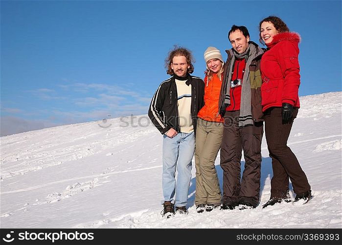 group of friends stand on snow on hillside