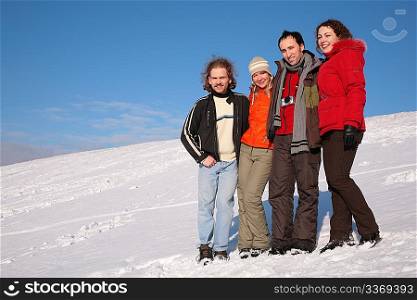 group of friends stand on snow on hillside