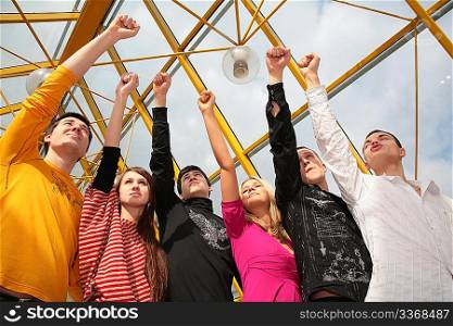 group of friends stands with raised fists on footbridge