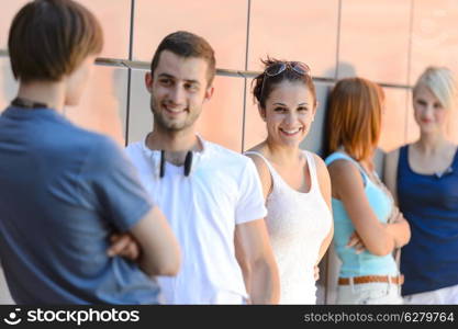 Group of friends students in row leaning against modern college wall