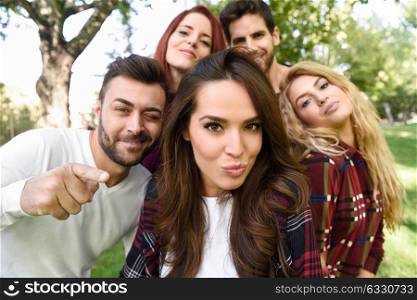 Group of friends taking selfie in urban background. Five young people wearing casual clothes.