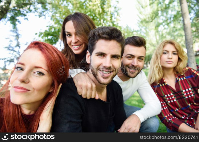 Group of friends taking selfie in urban background. Five young people wearing casual clothes.