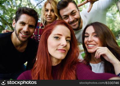 Group of friends taking selfie in urban background. Five young people wearing casual clothes.