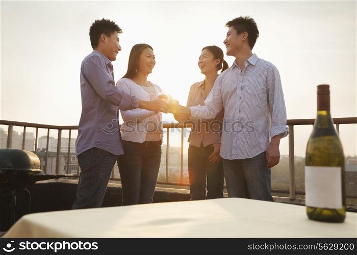 Group of Friends Toasting Each Other on Rooftop at Sunset