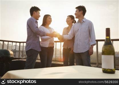 Group of Friends Toasting Each Other on Rooftop at Sunset