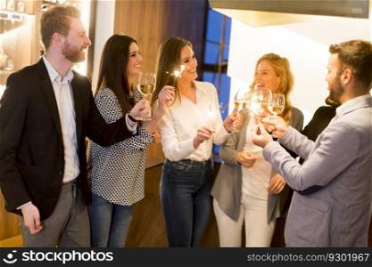 Group of friends toasting with white wine and enjoying evening drinks in bar