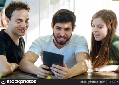 Group of friends using digital tablet and enjoying together in a coffee shop.