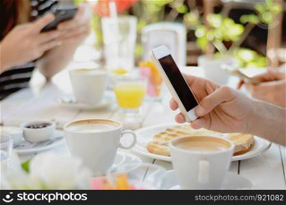 Group of friends using smartphone at coffee shop. Communication concept.