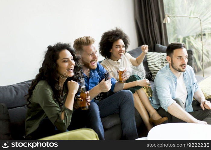 Group of friends watching TV , drinking cider and having fun in the room