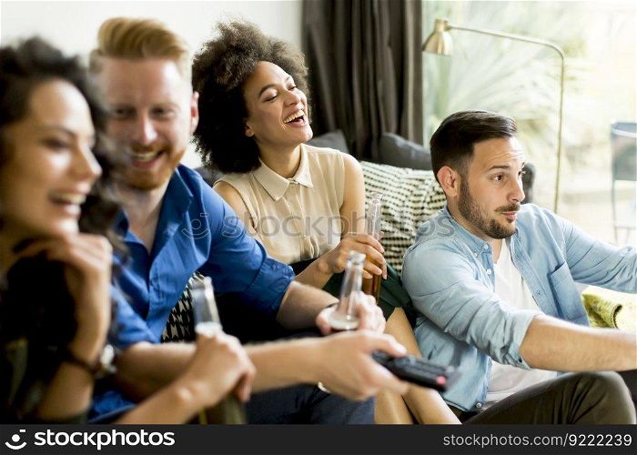 Group of friends watching TV , drinking cider and having fun in the room