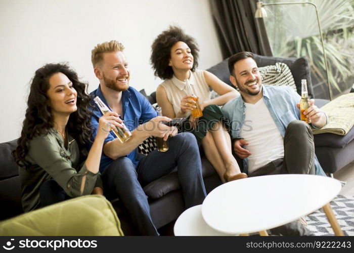 Group of friends watching TV , drinking cider and having fun in the room