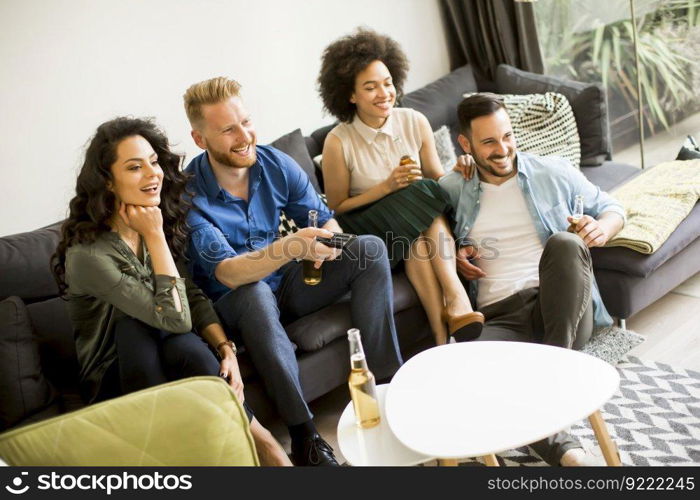 Group of friends watching TV , drinking cider and having fun in the room