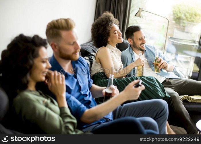 Group of friends watching TV , drinking cider and having fun in the room