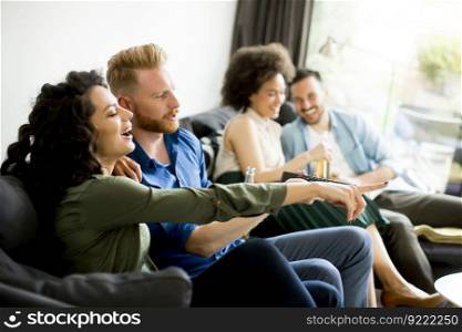 Group of friends watching TV , drinking cider and having fun in the room