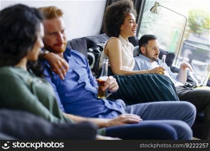 Group of friends watching TV, drinking cider  and having fun in the room