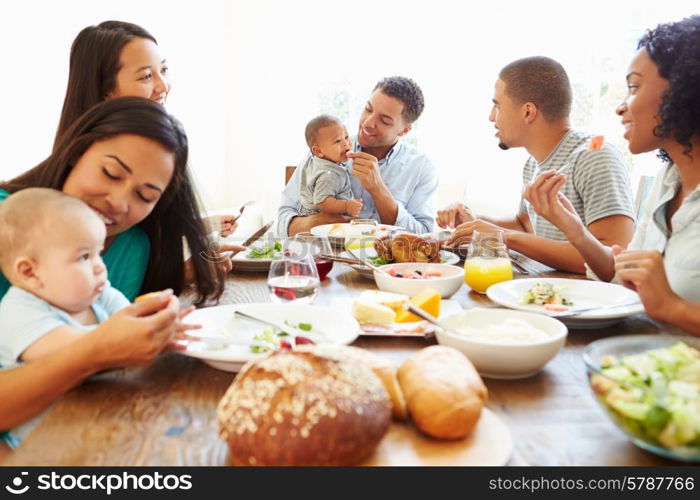 Group Of Friends With Babies Enjoying Meal At Home Together