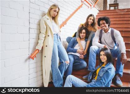 Group of friends with ethnic variety, sitting on some street steps having fun together outdoors.. Group of friends with ethnic variety, sitting on some street steps having fun together.