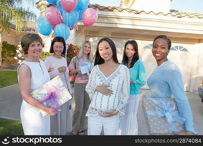 Group of friends with gifts for baby shower outside house