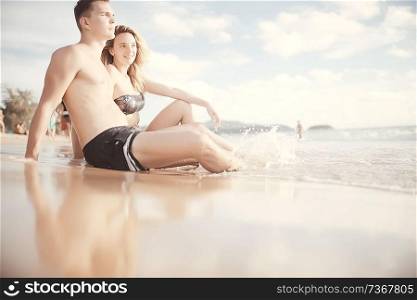 group of friends, youth sitting sunbathing on the beach / summer friends relaxing on the sea, vacation with friends on the coast tourism