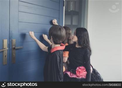 Group of girl and boy kids smiling and dress up as Halloween vampire costume and knock on door for trick or treat for Halloween night day theme coming soon together