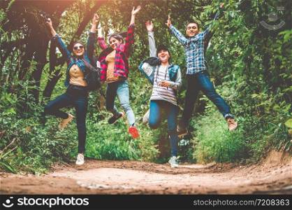 Group of happy Asian teenage adventure traveler trekkers group jumping together in mountain at outdoor forest background. Young hiker friends supporting each others as survival team travel and success