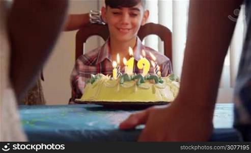 Group of happy children celebrating birthday at home, kids and friends having fun at party. Child blowing candles on cake. Slow motion
