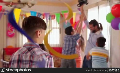 Group of happy children celebrating birthday at home, kids and friends having fun at party. Portrait of happy latino boy smiling, hispanic child looking at camera. Slow motion