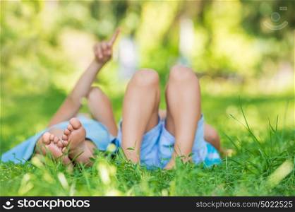 Group of happy children lying on green grass outdoors in summer park