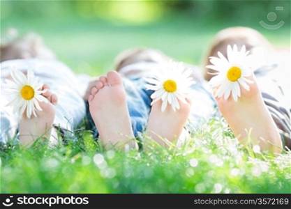 Group of happy children lying outdoors against green spring background