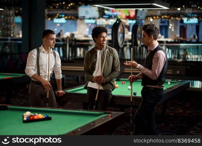 Group of happy friends enjoying billiard game, company of handsome young guys playing in pool. Company of handsome young guy playing in pool