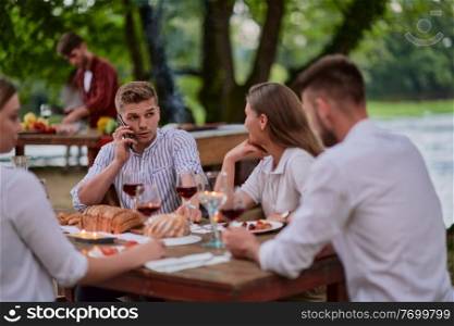 group of happy friends having picnic french dinner party outdoor during summer holiday vacation near the river at beautiful nature