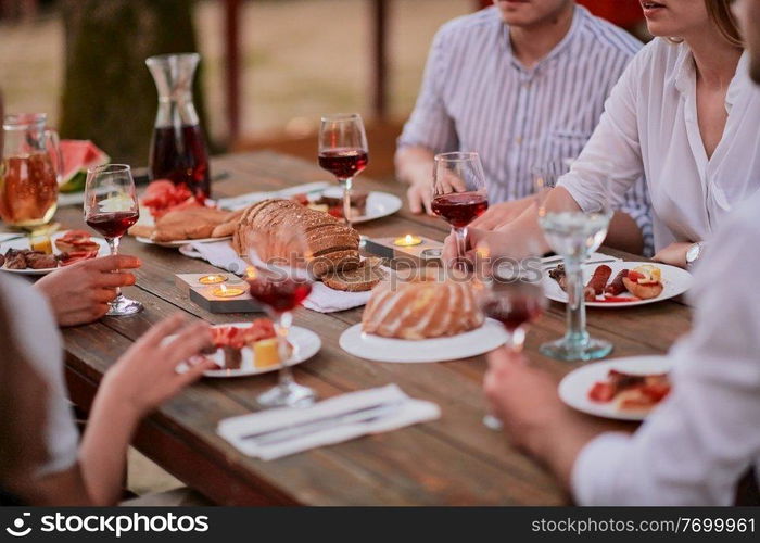 group of happy friends having picnic french dinner party outdoor during summer holiday vacation near the river at beautiful nature