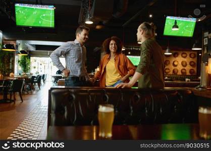 Group of happy friends resting and talking at bar or pub. Diverse interracial young people discussing football soccer match together sharing impressions. Group of happy friends resting and talking at bar or pub