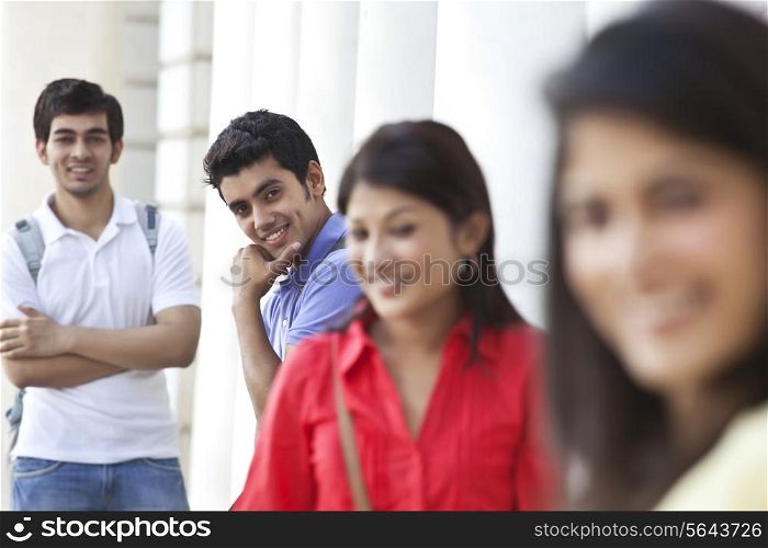 Group of happy friends standing against columns