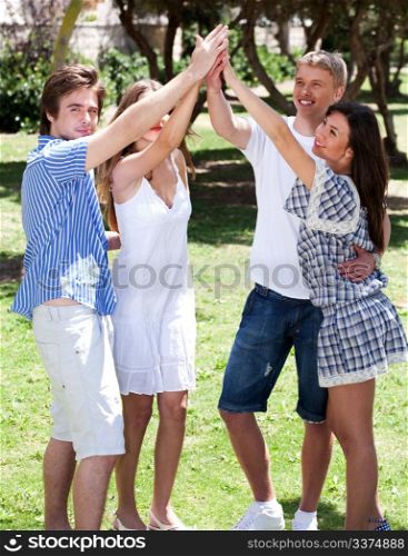 Group of happy friends with raised arms enjoying their day in park, outdoors
