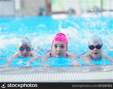 group of happy kids children at swimming pool class learning to swim