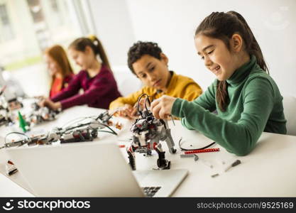 Group of happy kids programming electric toys and robots at robotics classroom