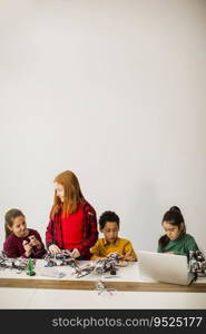 Group of happy kids programming electric toys and robots at robotics classroom