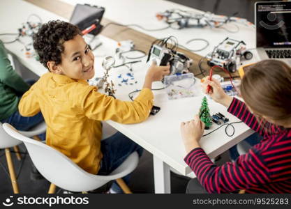 Group of happy kids programming electric toys and robots at robotics classroom