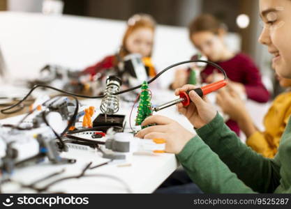 Group of happy kids programming electric toys and robots at robotics classroom